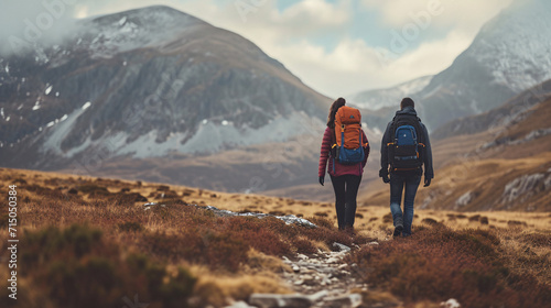 Couple trekking through a highland moorland landscape. Wilderness adventure and hiking concept with mountain backdrop 