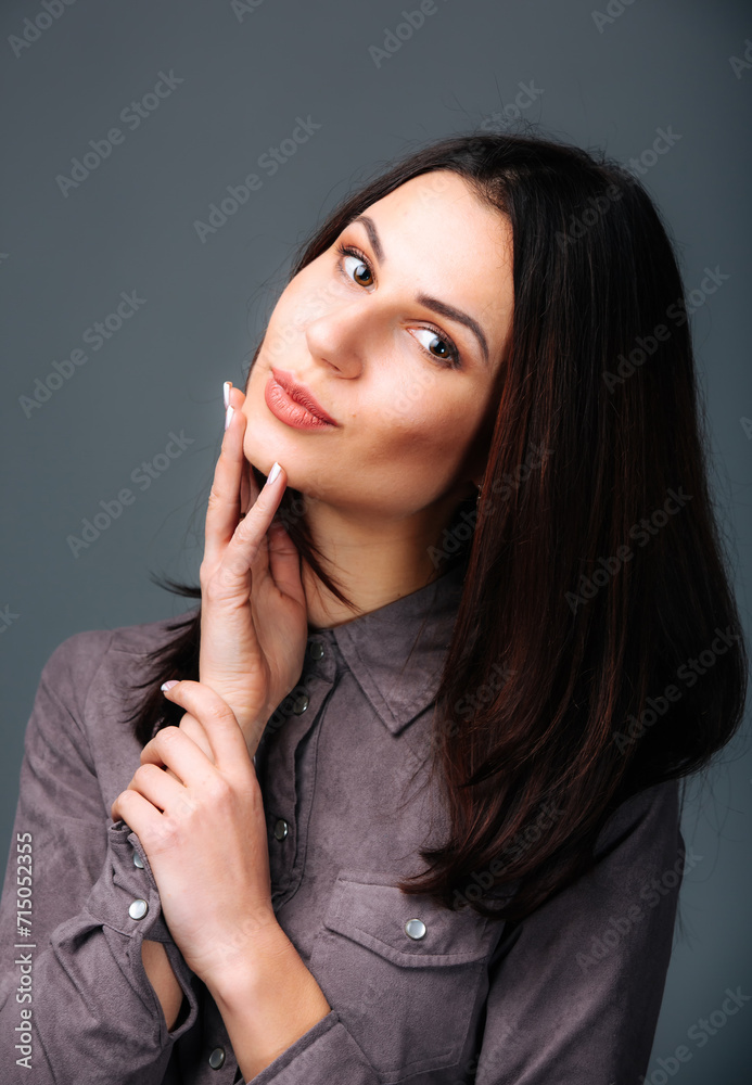 Woman Posing for Picture With Hand on Chin. A woman striking a pose, with her hand resting gently on her chin, as she smiles for the camera.