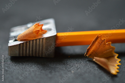 close up of pencil shavings, pencil sharpener and pencil on dark gray 