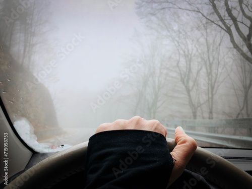 Hand on the steering wheel and fog seen from the car windshield 