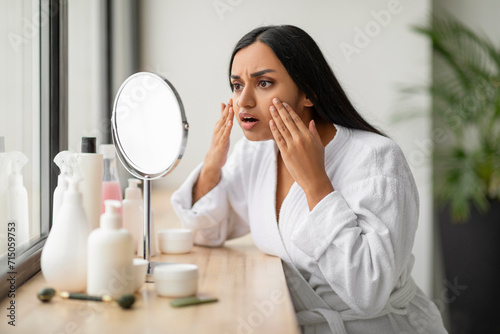 Shocked young indian woman looking at her face at mirror