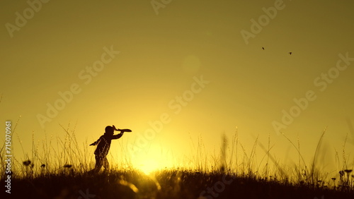 Child boy wants to become pilot astronaut. Teenager dreams of flying, becoming pilot, Airplane flight, Childhood. Happy Child boy plays with toy plane on field, sunset. Children play with toy airplane