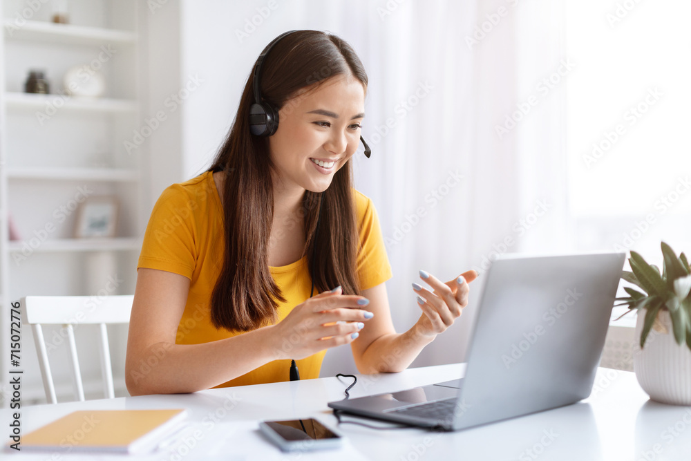 Portrait Of Smiling Asian Woman In Headset Making Video Call On Laptop Portrait Of Smiling Asian Woman In Headset Making Video Call On Laptop