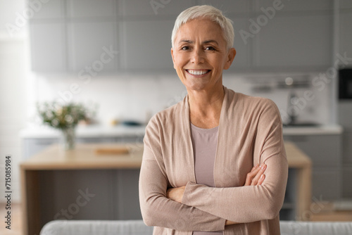 Portrait of confident senior woman with short hair crossing hands photo