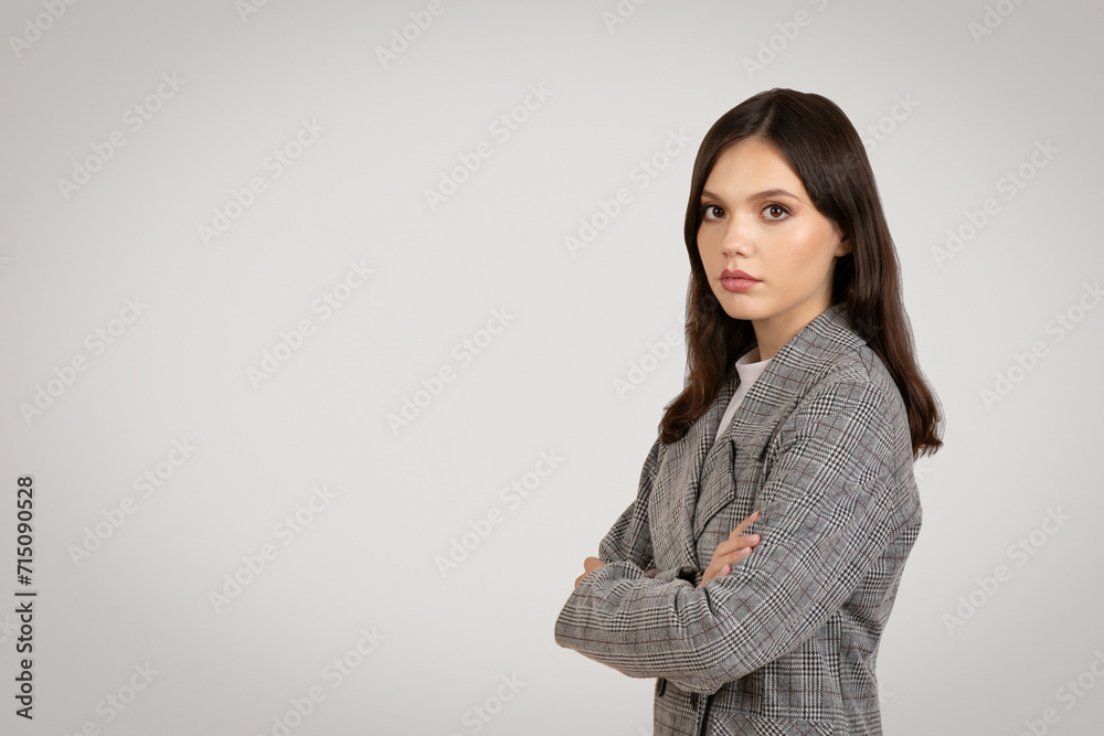Confident young woman in a plaid blazer, arms crossed Confident young woman in a plaid blazer, arms crossed