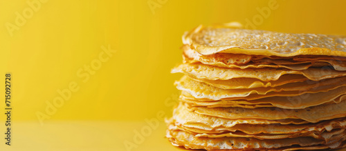 Stack of Freshly Made Golden Crepes, copy space. Golden stack of homemade crepes on a flat background. photo