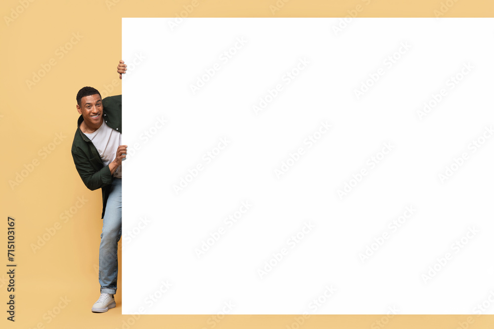 Excited african american guy posing next to advertising board Excited african american guy posing next to advertising board