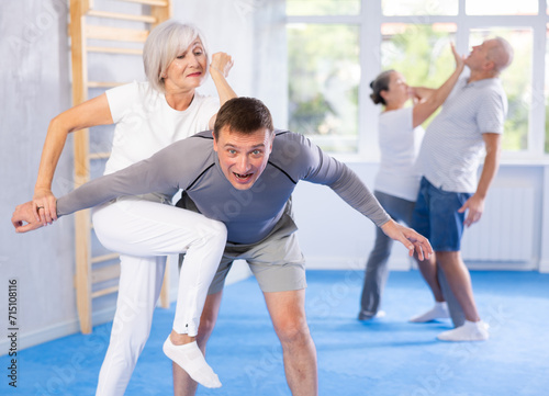 Tableau sur toile Senior woman train in pair with middle-aged coach to strike and reflect blows of enemy
