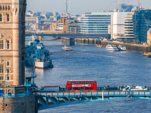 Aerial view of the Iconic Tower Bridge connecting Londong with Southwark on the Thames River in London, UK. Red London bus crossing the bridge. photo