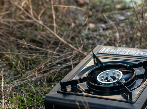 Camping gas stove is small, individual traveler lights a camp stove, warms hands on a mountain hike, compact and lightweight portable gas stove for cooking