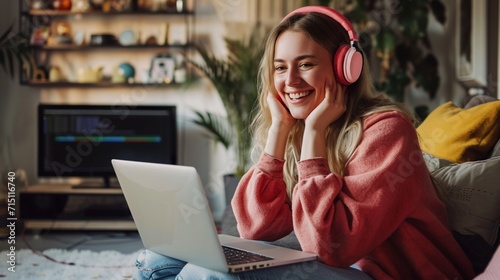 Cheerful young woman in headphones having web conference while working from home photo