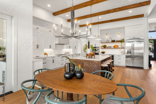 Kitchen and dining room in new luxury home with pendant lights, hardwood floors, stainless steel appliances, and large island