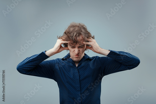 Curly-haired man winces, overwhelmed by intense discomfort