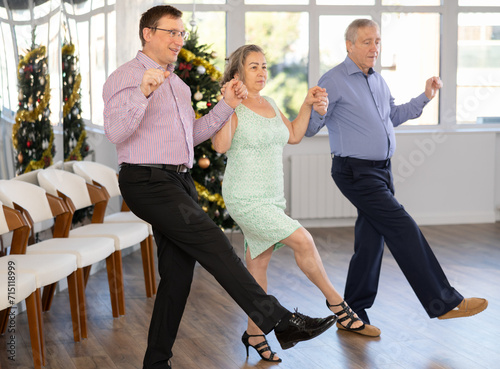 Group men and women dancing folk dance in row in studio.. photo