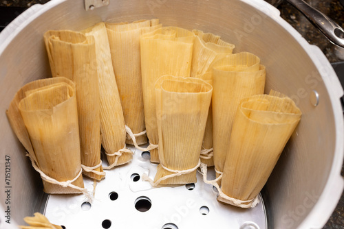 Preparation for steaming tamales in a large pan on the stove top, placed standing in rows. photo