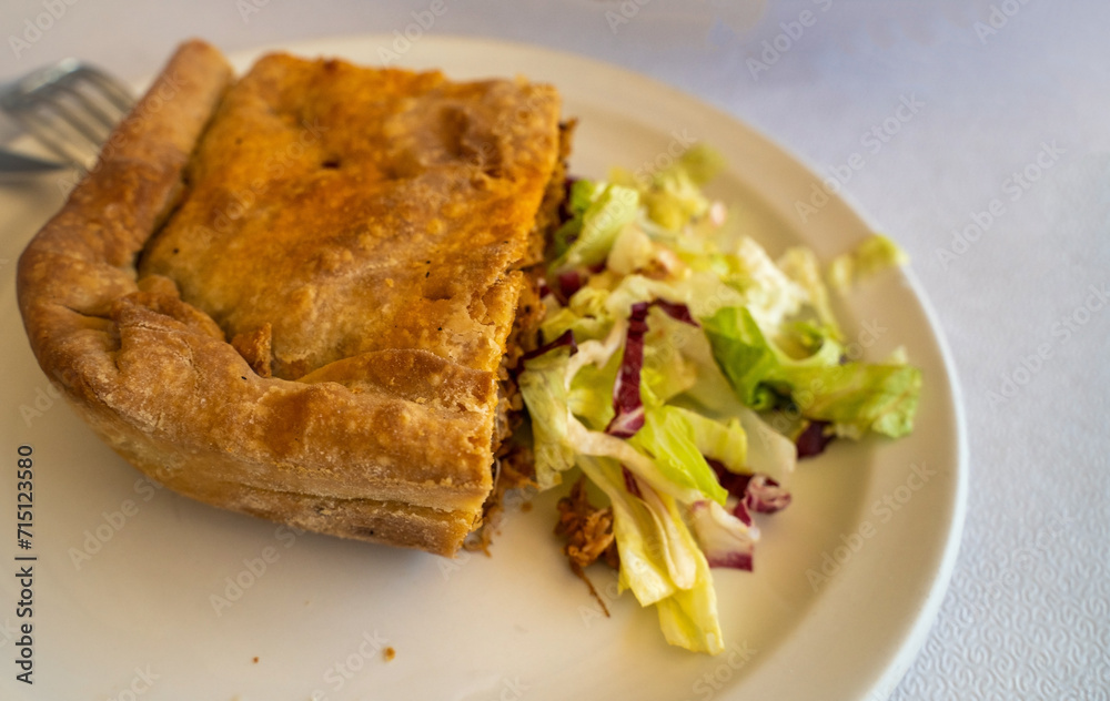 A greek cuisine puff pastry on a plate with pie stuffed with vegetables and chicken