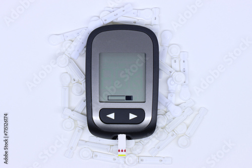Glucometer monitor screen in the middle with lancet needle. 