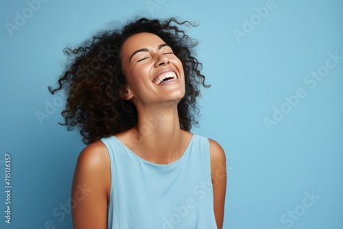 Cheerful young african american woman laughing and looking away on blue background