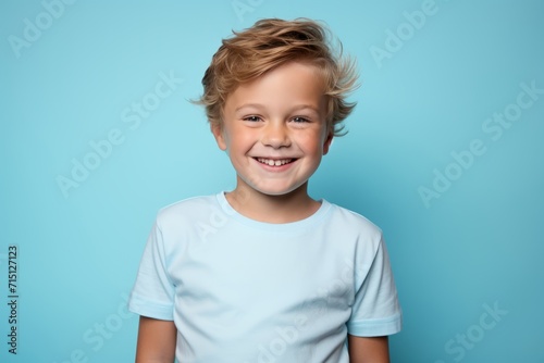Portrait of a smiling little boy in a blue T-shirt on a blue background