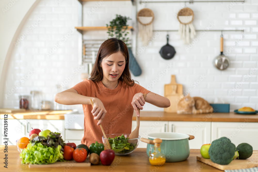 Portrait of beauty body slim healthy asian woman eating vegan food healthy with fresh vegetable salad in kitchen at home.diet, vegetarian, fruit, wellness, health, green food.Fitness and healthy food.