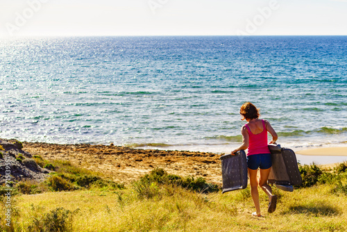 Woman on beach carrying deckchair