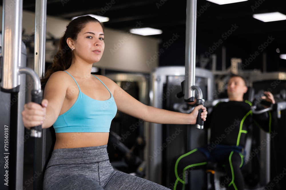 Fototapeta premium Athletic woman is engaged in the simulator - develops biceps and triceps