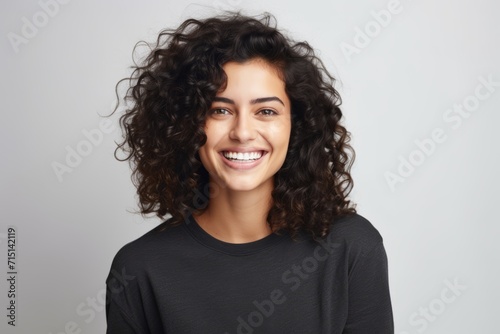 Portrait of a beautiful young woman with curly hair, over grey background © Inigo