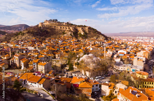 Picturesque aerial view of Kutahya cityscape with similar brownish tiled roofs on residential buildings located at foot of ancient castle hill on sunny winter day, Turkey photo