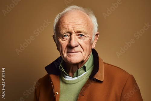 Portrait of an elderly man in a brown coat. Studio shot.