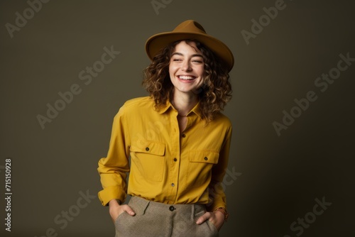 Cheerful girl in yellow shirt and hat posing on dark background