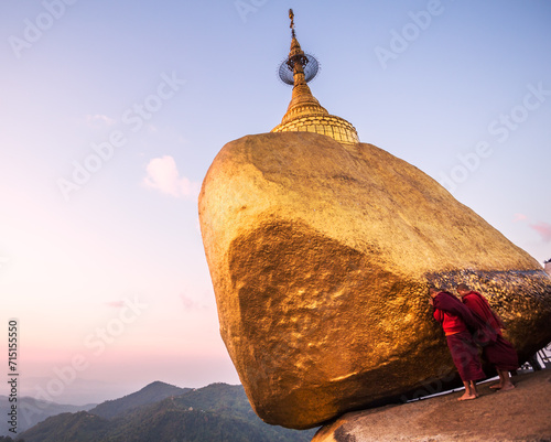 Two buddhist monks praying at the Golden rock, Myanmar photo