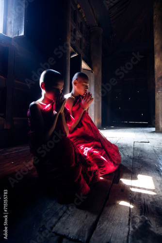 Two buddhist novice monks praying inside a monastery. Myanmar photo