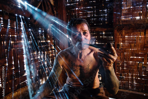 Portrait of asian man shirtless with tattoo smoking pipe, Myanmar photo