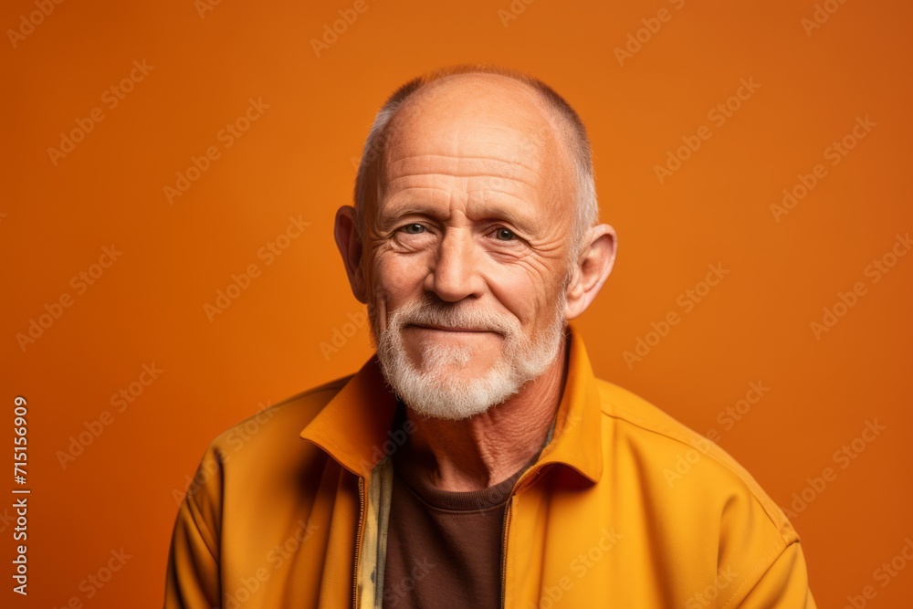 Portrait of an old man in a yellow jacket on a orange background. Portrait of an old man in a yellow jacket on a orange background.