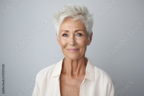 smiling senior woman looking at camera over grey background with copy space