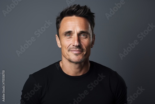 Portrait of a handsome man in black t-shirt on grey background © Inigo