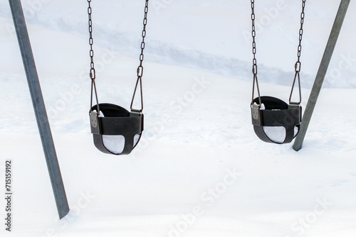 Playground with baby swings in park, covered with snow in winter © Iryna