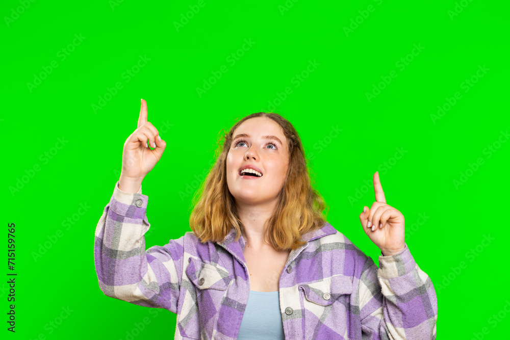 Young woman showing thumbs up and pointing empty place over head, advertising area for commercial text, copy space for goods promotion advertisement. Girl isolated on chroma key background. Lifestyles