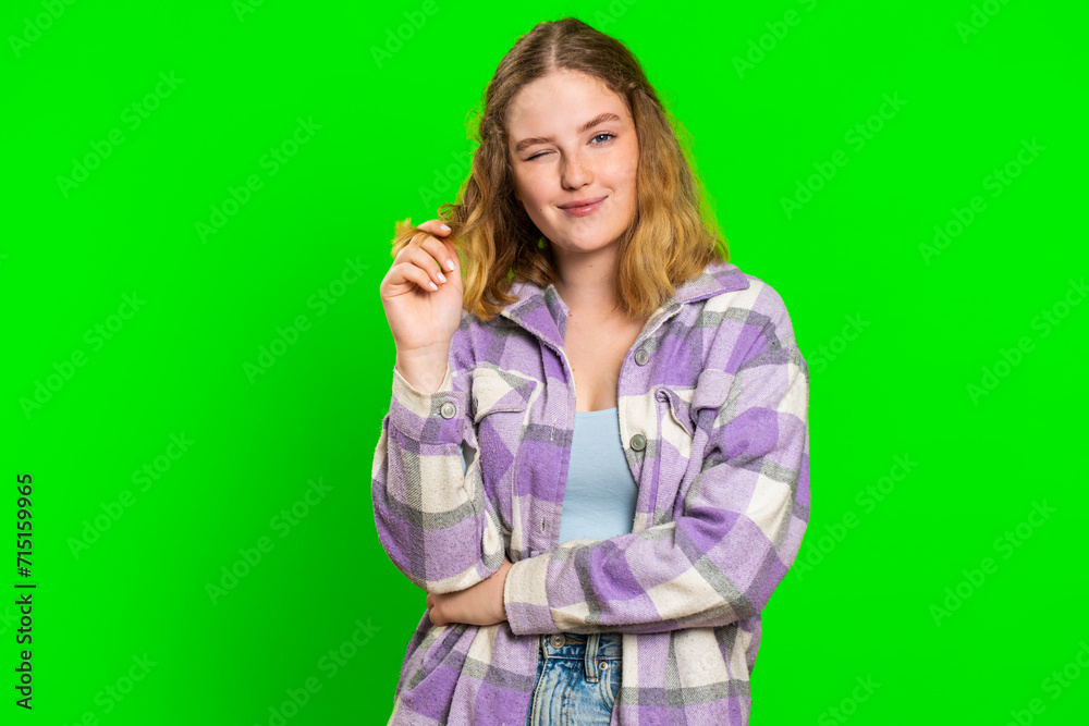 Smiling playful happy young caucasian woman blinking eye, looking at camera with smile, winking, flirting, expressing optimism, good news. Charming redhead girl isolated on green chroma key background Smiling playful happy young caucasian woman blinking eye, looking at camera with smile, winking, flirting, expressing optimism, good news. Charming redhead girl isolated on green chroma key background