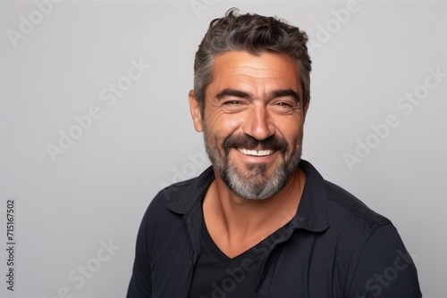 Portrait of a handsome mature man smiling at the camera while standing against grey background