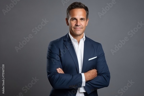 Portrait of a confident mature businessman with arms crossed over grey background