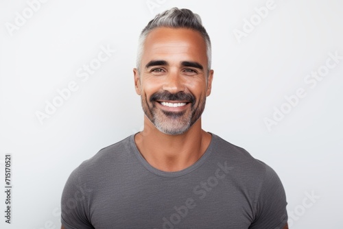 Portrait of handsome mature man smiling and looking at camera against grey background