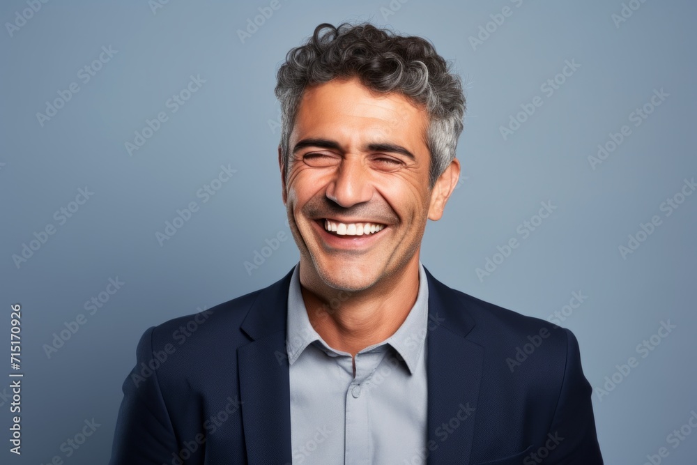 Handsome middle age man laughing and looking at camera on grey background Handsome middle age man laughing and looking at camera on grey background