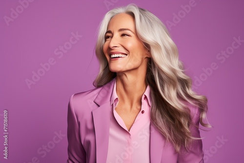 Portrait of a happy mature businesswoman smiling and looking away against purple background