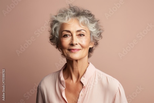 Beautiful senior woman with grey hair and a pink shirt. Studio shot.