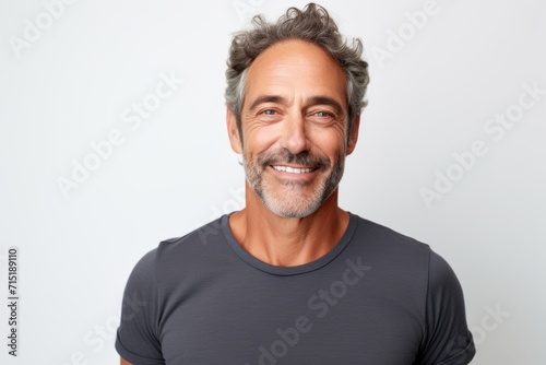 Portrait of handsome mature man smiling and looking at camera against grey background