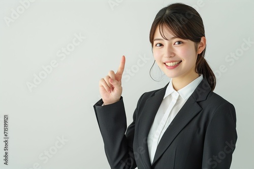 指をさす日本人の女性ビジネスマンウーマンのポートレート写真（白背景・会社員・スーツ・若手・OL・新入社員・窓口・案内）