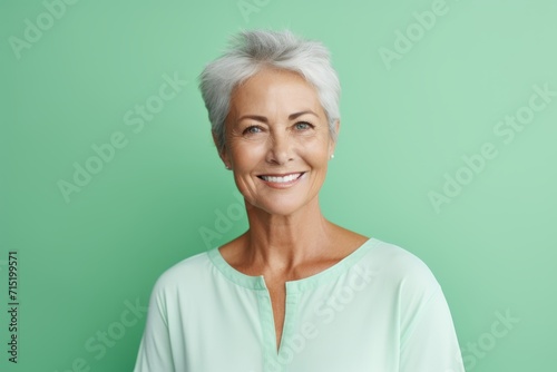Portrait of happy senior woman smiling at camera over green background.