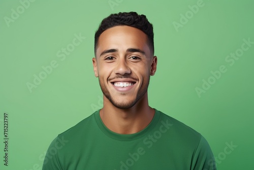 Portrait of happy young man in green t-shirt against green background