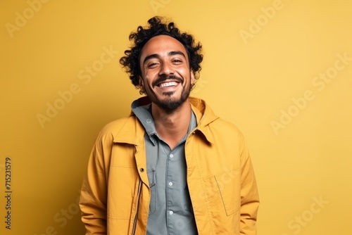 Portrait of a happy young african american man in yellow jacket on yellow background © Inigo